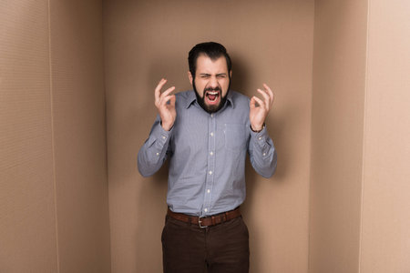 stressed man screaming in cardboard box