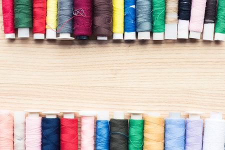 colorful frame of stitchings over wooden background with copy space