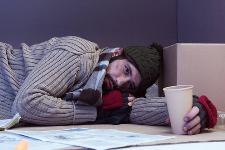muddy homeless poor man asking for alms in cardboard box
