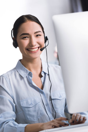 portrait of smiling asian call center operator in headset looking at cameraの写真素材