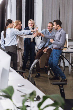 group of businesspeople clinking glasses of champagne in officeの写真素材