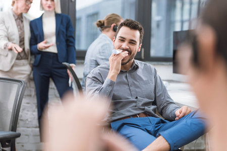 portrait of cheerful businessman looking at camera while sitting at workplace in officeの写真素材
