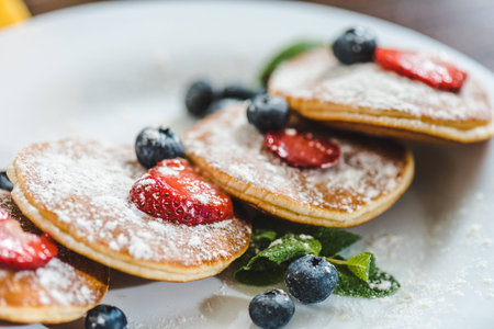 closeup pancakes with berries and mint on white plate