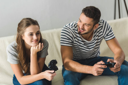 beautiful young couple playing games with gamepads at homeの写真素材