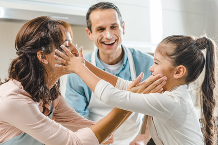 cheerful family at kitchen, mother and daughter gently touching each other faces and smilingの写真素材