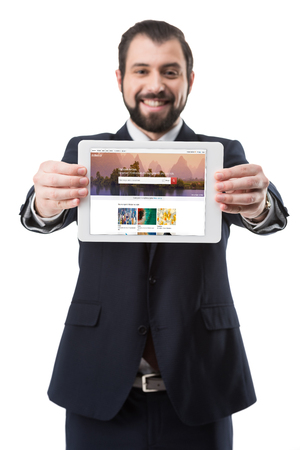 Smiling businessman showing digital tablet with shutterstock photo stock website, isolated on whiteのeditorial素材
