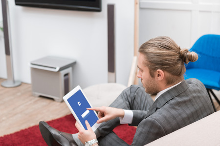 businessman using digital tablet with facebook website at homeのeditorial素材