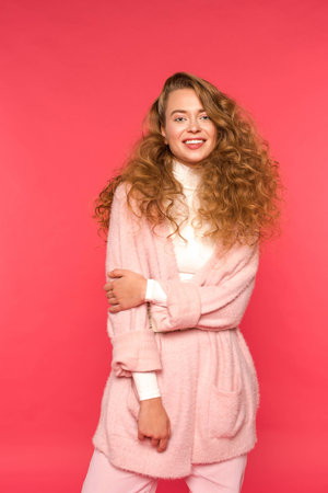 smiling woman in warm clothes looking at camera isolated on redの写真素材