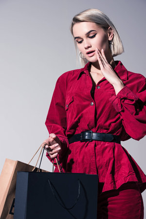 attractive fashionable girl in red trendy clothes with shopping bags, on greyの写真素材