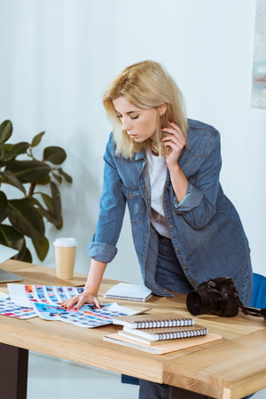 portrait of focused photographer looking at photoshoot samples at workplace in officeの写真素材