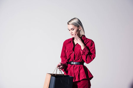 beautiful elegant girl in red trendy clothes with shopping bags, isolated on greyの写真素材