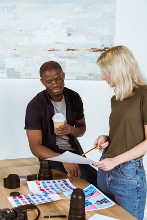 multicultural photographers discussing portfolio together at workplace in officeの写真素材