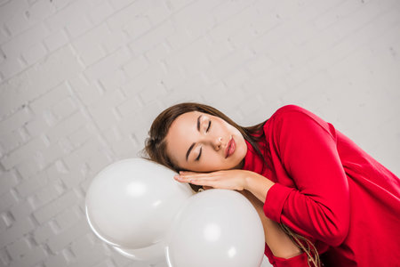 Woman posing and sleeping on white balloonsの写真素材