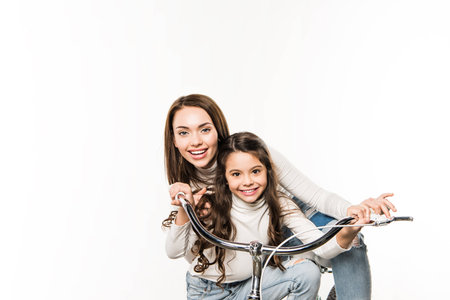 Smiling Mother and daughter with bicycle looking at camera isolated on whiteの写真素材