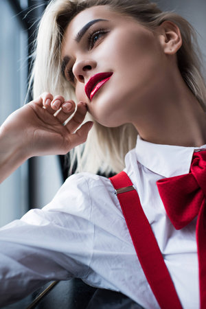 attractive blonde girl with red lipstick posing at windowの写真素材