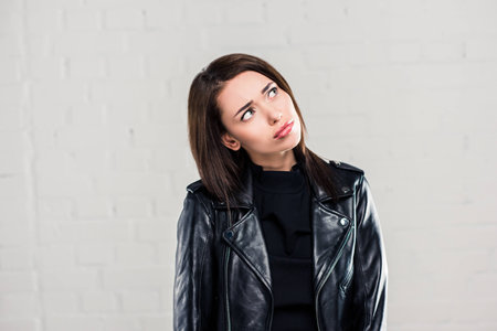 Upset stylish woman in leather jacket looking upの写真素材