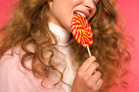 Cropped image of beautiful woman biting lollipop on redの写真素材