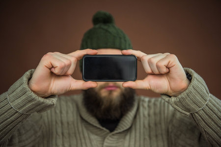 Man holding black smartphone in front of face