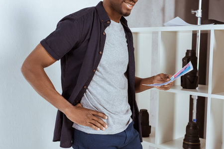 cropped shot of smiling african american man with papers in hand standing in studioの写真素材