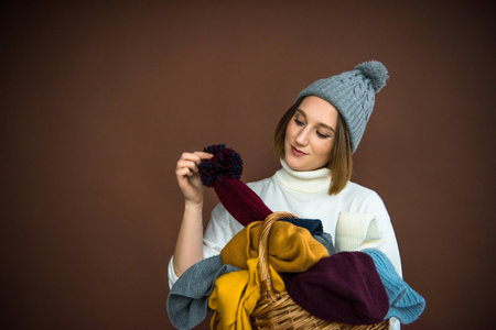 woman taking hat from wicker basket isolated on brown