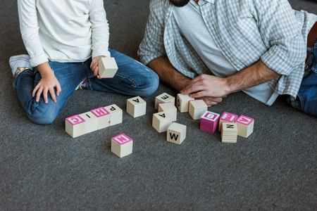 cropped image of father with daughter making words by cubes with letters at homeの写真素材