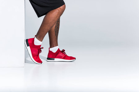 cropped shot of young african american sportsman in red sneakers on greyの写真素材