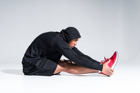 side view of young african american sportsman stretching on greyの写真素材