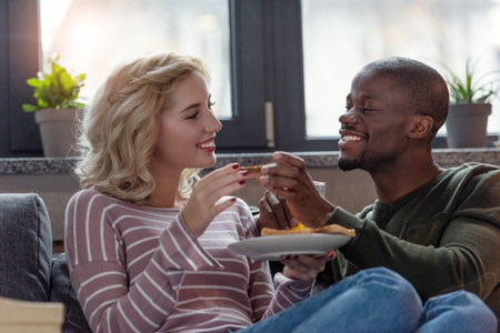 portrait of happy multicultural young couple having breakfast together at homeの写真素材