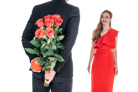 cropped shot of man presenting roses and heart shaped gift box to beautiful girlfriend at st valentines day isolated on whiteの写真素材