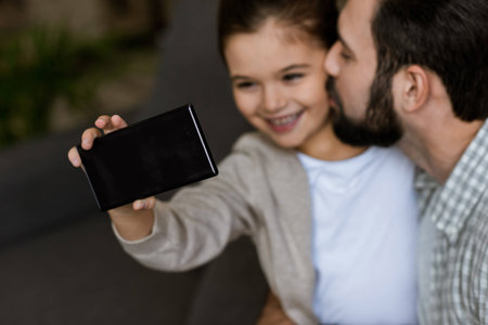 cheerful father with daughter taking selfie on smartphone at homeの写真素材