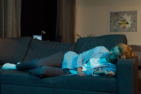 tired young woman sleeping on sofa at homeの写真素材