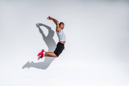side view of young african american sportsman jumping on greyの写真素材