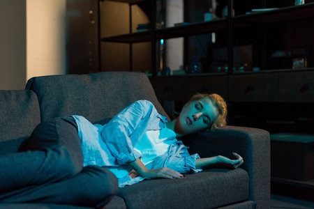 tired young woman sleeping on sofa at homeの写真素材