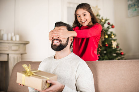 smiling daughter covering father eyes from backの写真素材