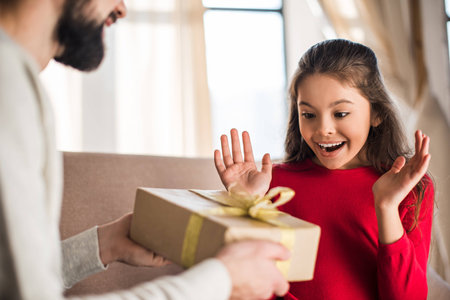 father presenting gift box to excited daughterの写真素材