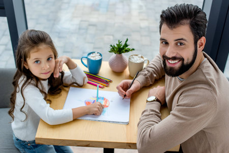 father and daughter drawing together and looking at cameraの写真素材