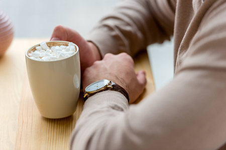 cropped image of man holding cup of coffee with marshmallow