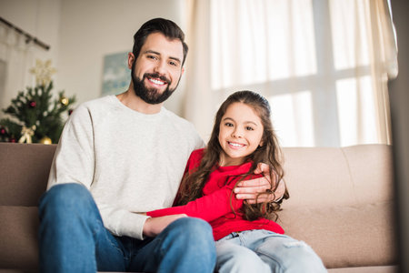 happy father and daughter hugging and looking at camera