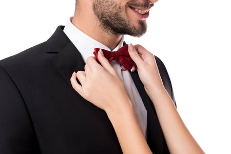 cropped image of girlfriend fixing boyfriends tie bow isolated on whiteの写真素材