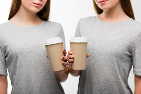 partial view of women holding coffee to go in hands isolated on whiteの写真素材
