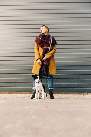 fashionable woman with puppy on dog lead standing on streetの写真素材