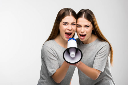 portrait of young twins screaming into loudspeaker in handsの写真素材