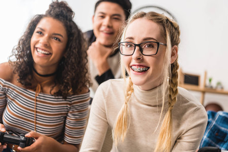 smiling teenage multicultural girls playing video gameの写真素材
