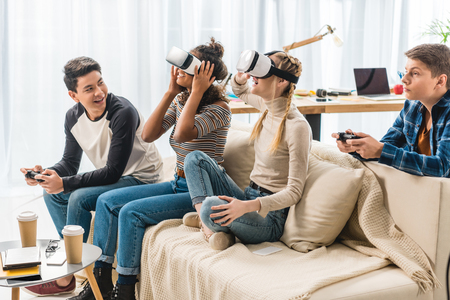 excited multicultural teen girls watching something with virtual reality headsetsの写真素材