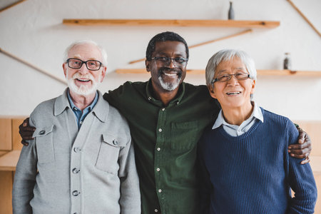group of multiethnic senior friends embracing and looking at cameraの写真素材