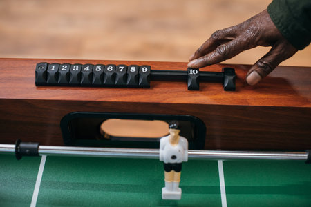 cropped shot of african american man moving counter on table football