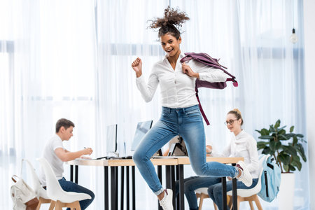 young african american student girl jumping in classroom with friends
