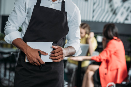 cropped shot of waiter in apron with notepad at cafeの写真素材