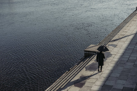 high angle view of man walking by river shore with umbrellaの写真素材