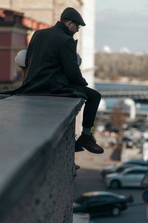 handsome middle aged man sitting on roof of building